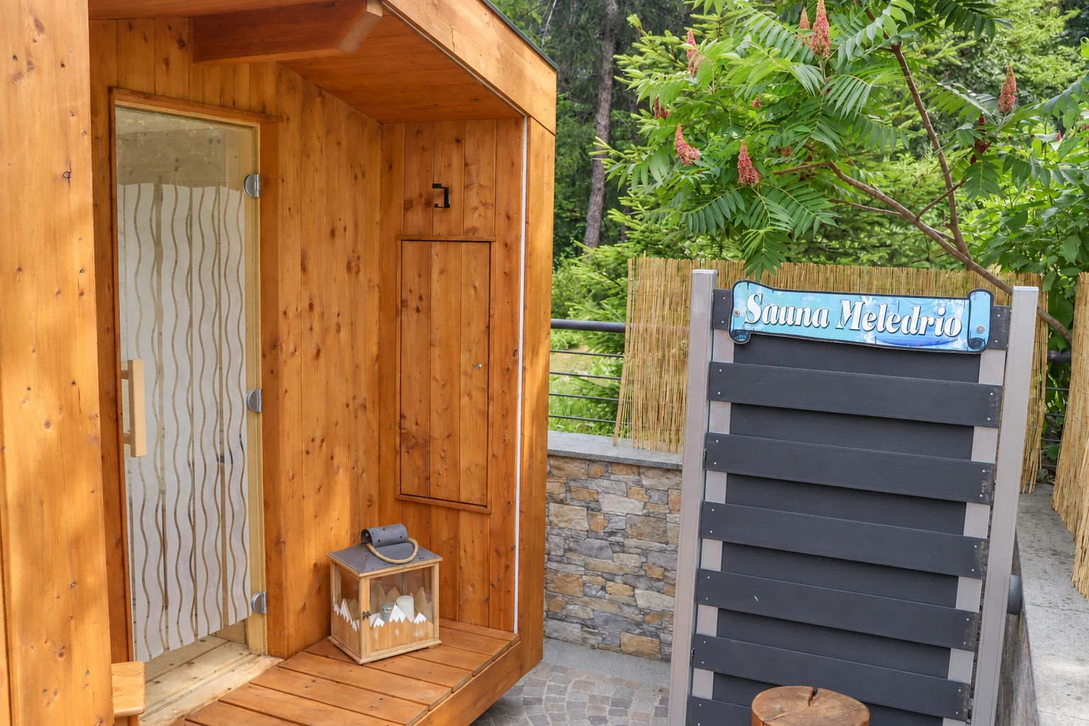 L’ingresso in legno con la lanterna e l’insegna Sauna Meledrio